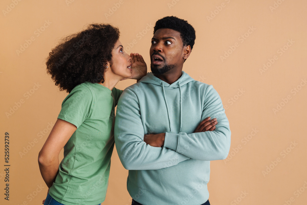 Black excited woman whispering secret at man's ear Black excited woman whispering secret at man's ear