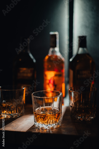 bottle and glass of whiskey with ice on a wooden background