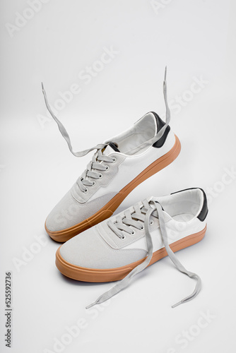 White leather men sneakers isolated on gray background. Fashionable stylish sports casual shoes. Creative minimalistic layout with footwear Mock up for your design Advertising for shoe store
