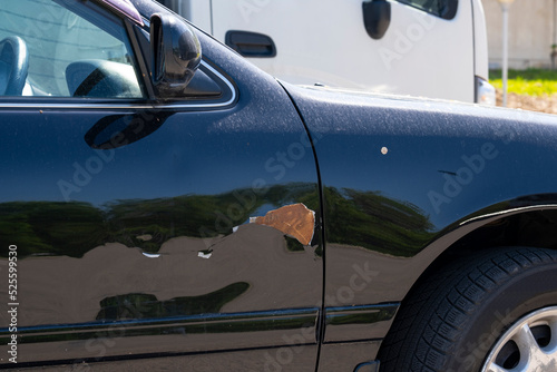 Rust on the car door, paint damage and metal corrosion.
