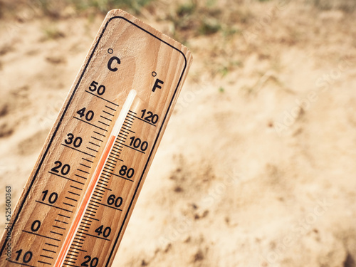 Fotografi Wooden thermometer showing high temperatures over 36 degrees Celsius on sunny day on background of dry sandy ground