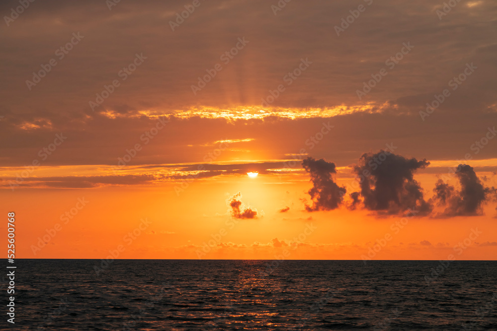 Beautiful sunset over the sea with bright orange clouds.