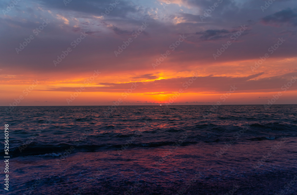 Beautiful sunset over the sea with bright orange clouds.