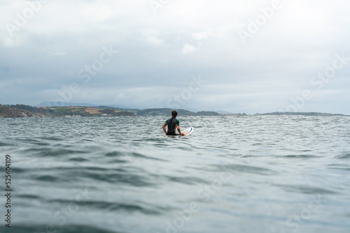 Surfer waiting for a wave in the sea with a surfboard 