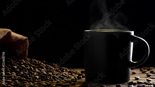 Hot Coffee Cup Concept. Close-up black coffee cup, mug with beautiful steaming smoke, classic vintage coffee grinder espresso manual, beans, burlap on on old wooden table dark, black background. Hot D photo