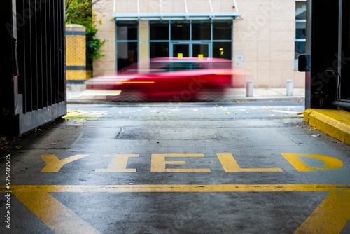 Canvas Print Yellow yield sign at the exit of a car park