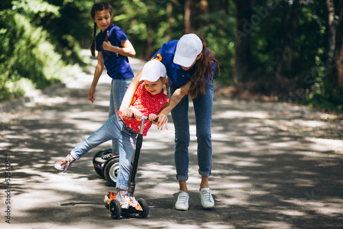 Mother with daughters on scooter having fun in park