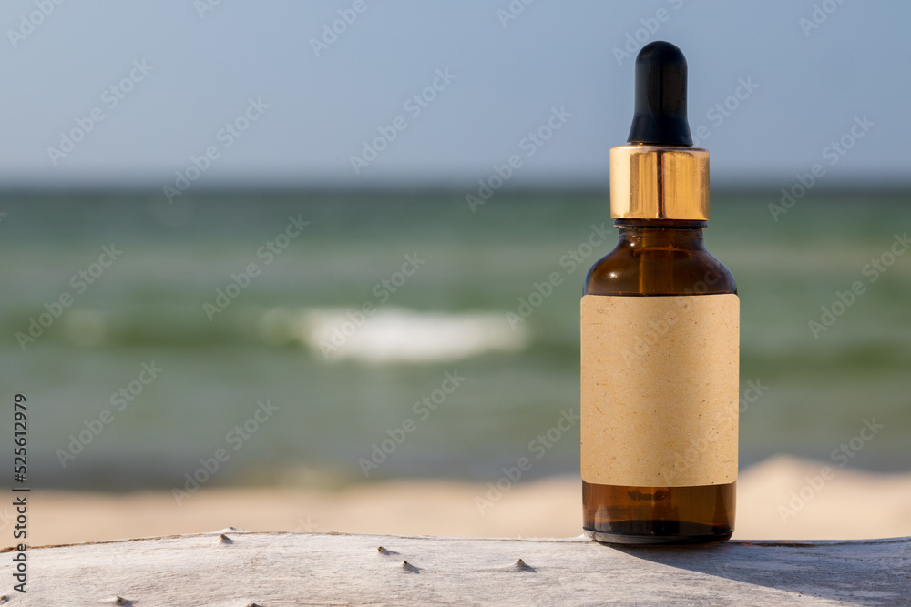 Glass bottle with essential oil serum cosmetic product background beach sand, product presentation. Empty label, copy space. Mockup for product presentation, wooden base and beach backdrop. Glass bottle with essential oil serum cosmetic product background beach sand, product presentation. Empty label, copy space. Mockup for product presentation, wooden base and beach backdrop.