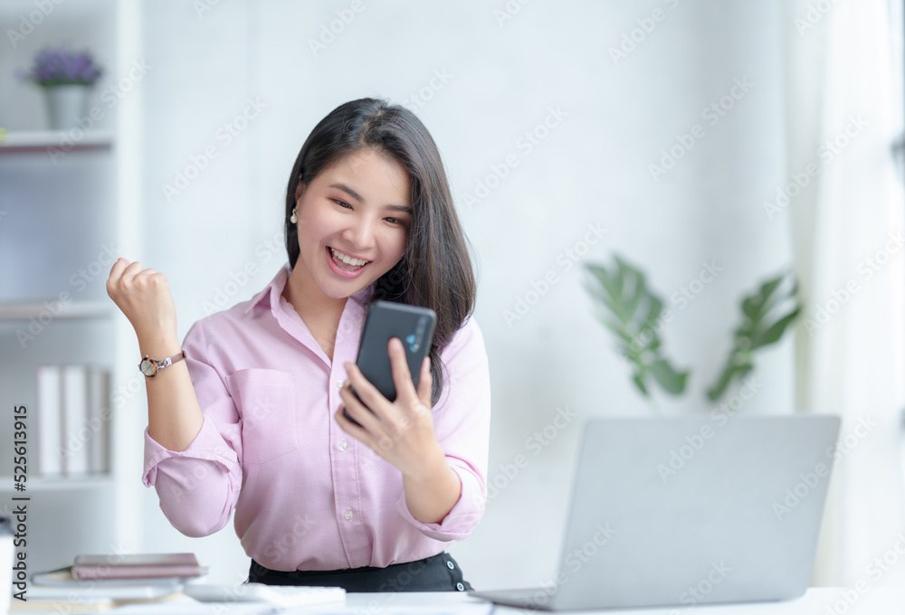Happy young Asian business woman Successful excited raised hands rejoicing with smartphone. Happy young Asian business woman Successful excited raised hands rejoicing with smartphone.