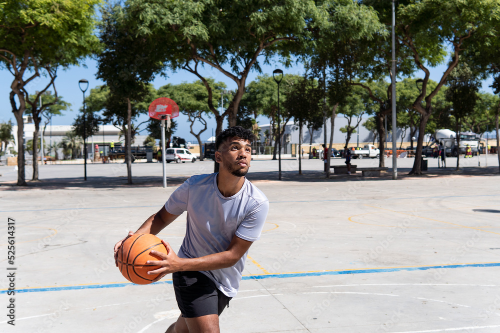 Young muslim man playing street basketball on a city court, training and sport concept