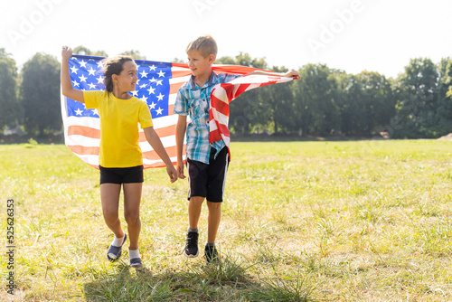 Children sit with American flag outdoors.