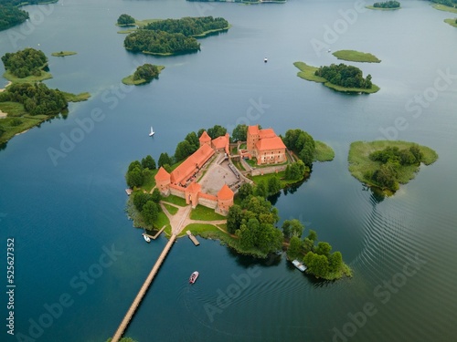 Aerial shot of the Trakai castle surrounded by green trees over the Galves lake in Trakai, Lithuania photo