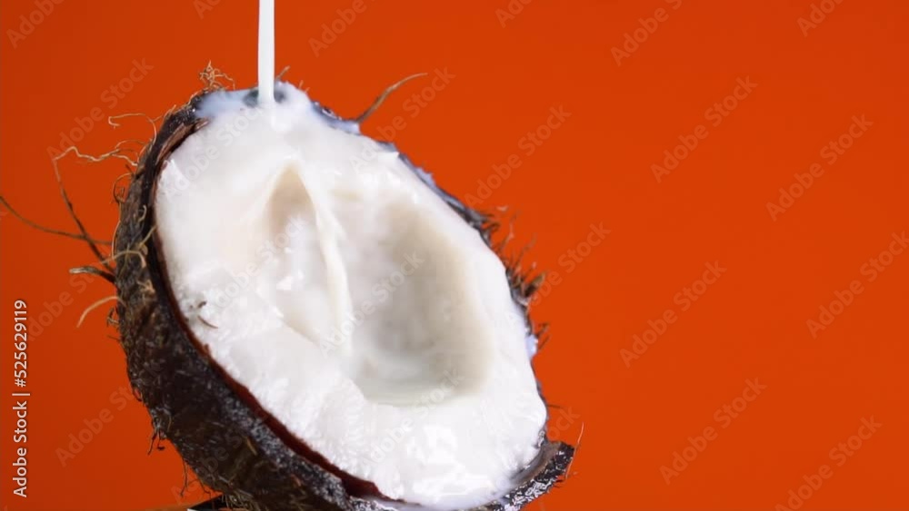 Drops of coconuts oil over red background, dripping coconut water, coconut milk pouring. Making