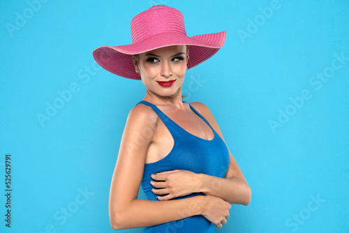 Smiling young woman with pink summer hat on a blue background © vladimirfloyd