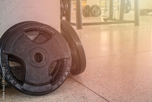 15kg barbell wheel inside an exercise gym leaning against a building column against a blurred background of exercise machines. photo