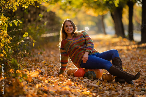 Smile woman sitting on the pumpkin on the autumanl maple leaves photo