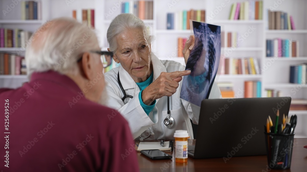 Obraz premium Woman doctor shows X-Ray film to an elderly man old patient, provide professional medicare health insurance.