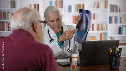 Woman doctor shows X-Ray film to an elderly man old patient  provide professional medicare health insurance.