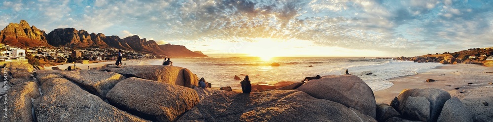 Fototapeta premium Panoramic view of rocks on Camps bay beach in cape town, south Africa at sunset