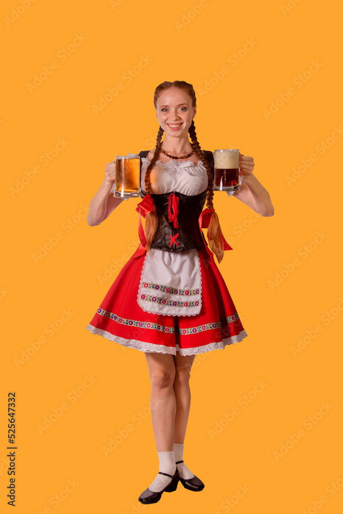 sexy oktoberfest waitress dressed in traditional bavarian dress serving two big mugs of beer isolated on yellow background
