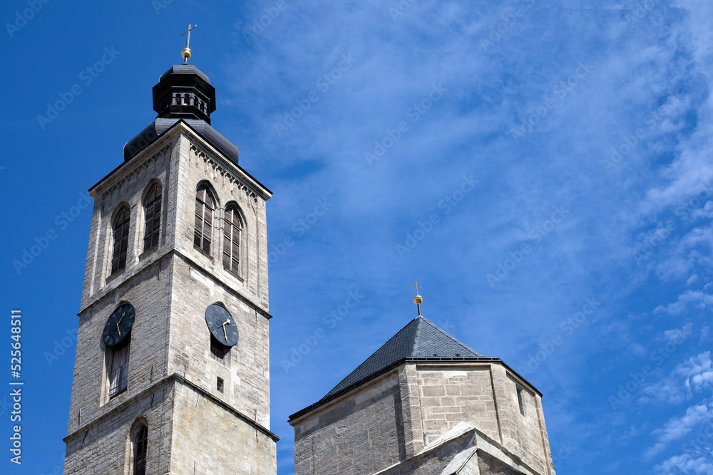 a clock tower of the catholic church against the blue sky on sunny day with copy space