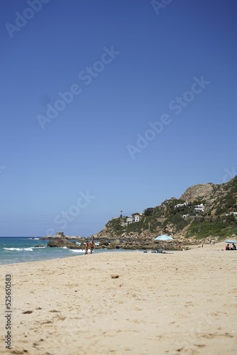 Vertical shot of a sandy beach with many tourists againgst a gradient sky on a sunny day photo