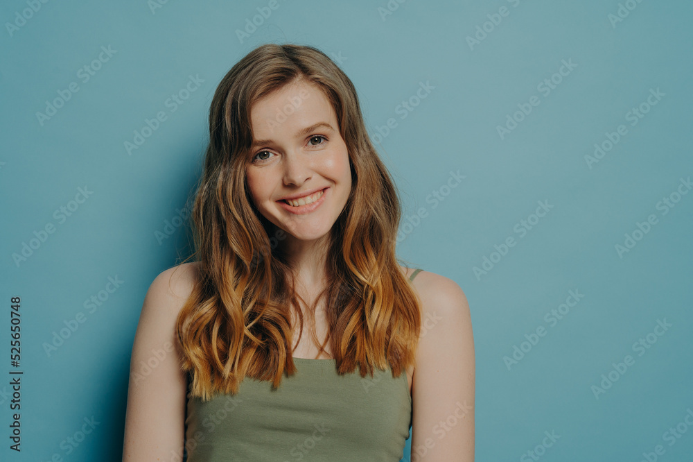 Positive joyful teen girl in top tank demonstrating optimism and happiness, isolated over blue wall Positive joyful teen girl in top tank demonstrating optimism and happiness, isolated over blue wall