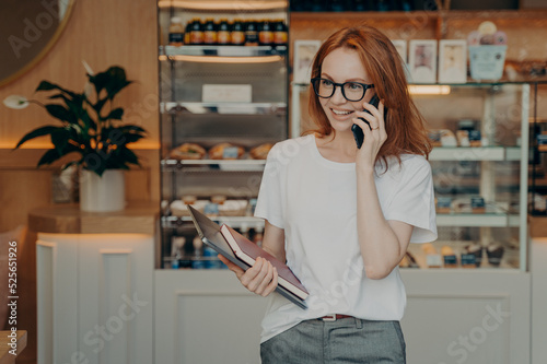 Smiling redhead young woman has telephone conversation enjoys positive talk