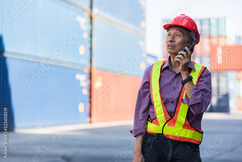 senior factory worker or engineer talking on walkie talkie in containers warehouse storage