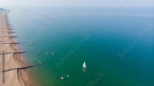 Drone shot of beach and Seafront with paddle boarders in Tankerton in Kent, United Kingdom photo