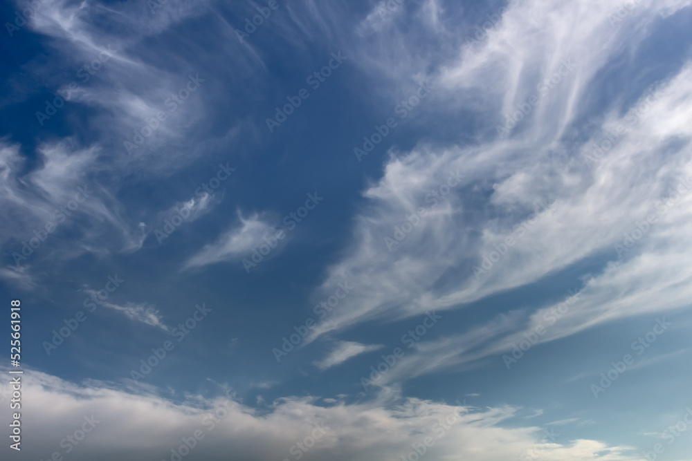 Picturesque cloudscape background with light spindrift clouds on a dark blue sky
