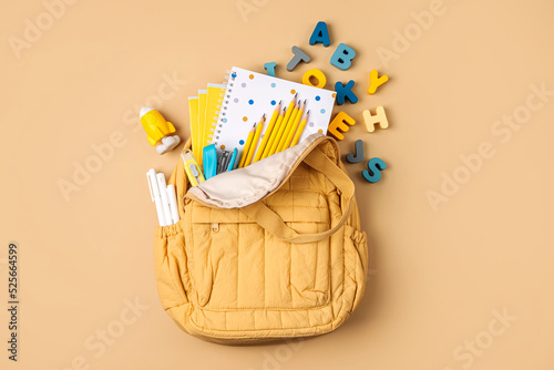 Opened School backpack with stationery. Primary school or preschool, kindergarten. Kids Backpack on beige background. photo