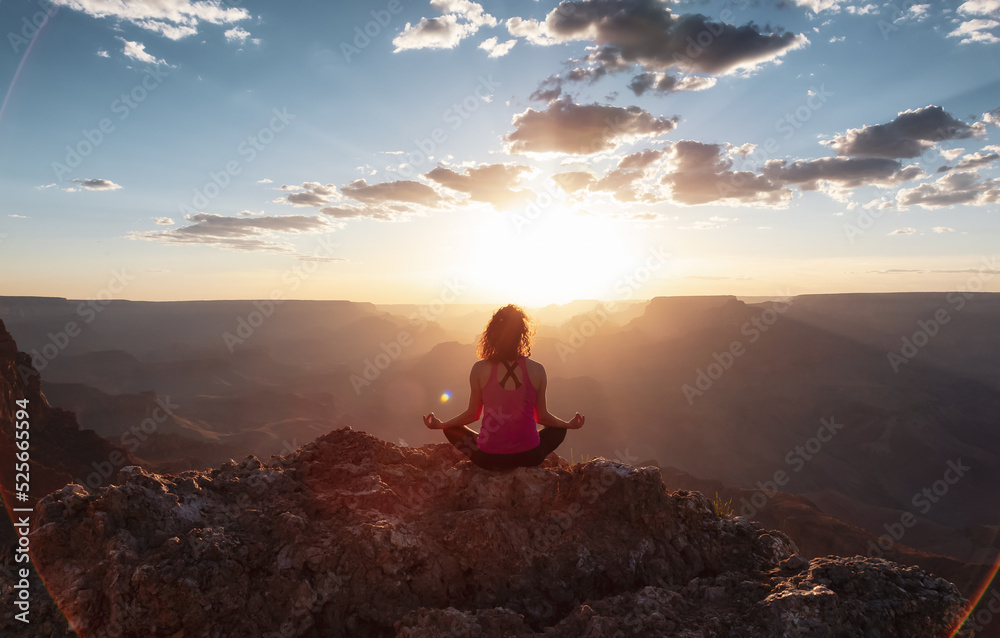 Adventurous Traveler woman doing meditation on Desert Rocky Mountain American Landscape. Cloudy Sunny Sky. Grand Canyon National Park, Arizona, United States. Adventure Travel