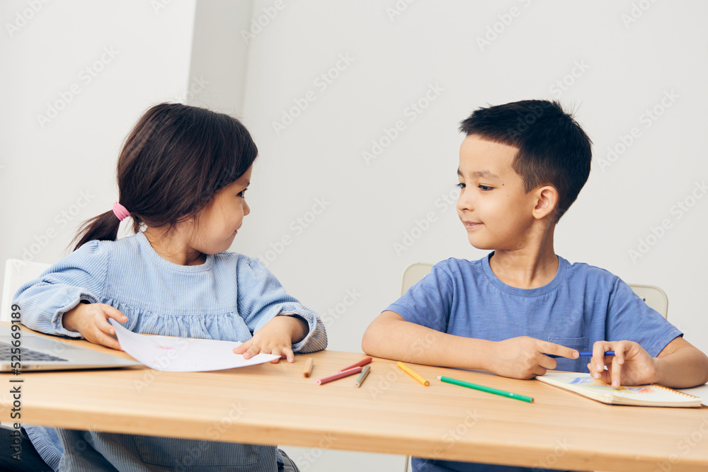 small children sit at the table during class and look at each other small children sit at the table during class and look at each other