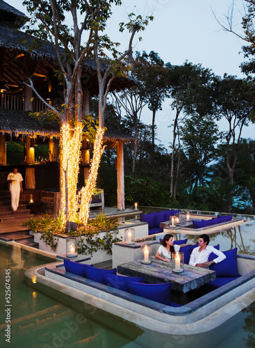 A couple has sunset cocktails at an outdoor resort lounge. Yao Noi, Koh Yao Noi, Thailand.
