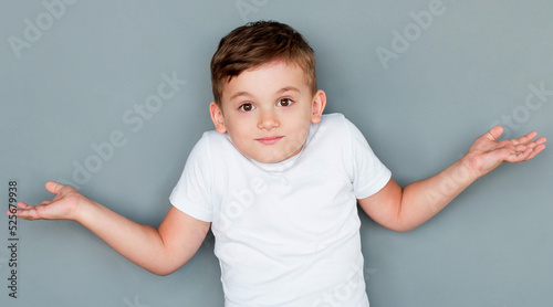 Little cute boy kid wearing casual white tshirt clueless and confused expression with arms and hands raised. doubt concept.