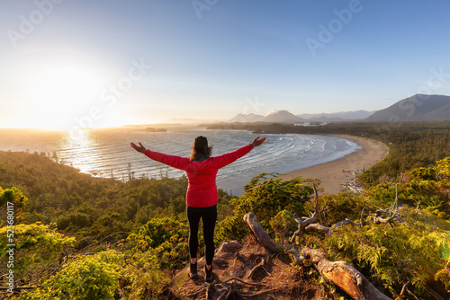 Adventurous Woman Hiker overlooking Sandy Beach on the West Coast of Pacific Ocean. Canadian Nature Landscape Background. Cox Bay Lookout, Tofino, Vancouver Island, BC, Canada.