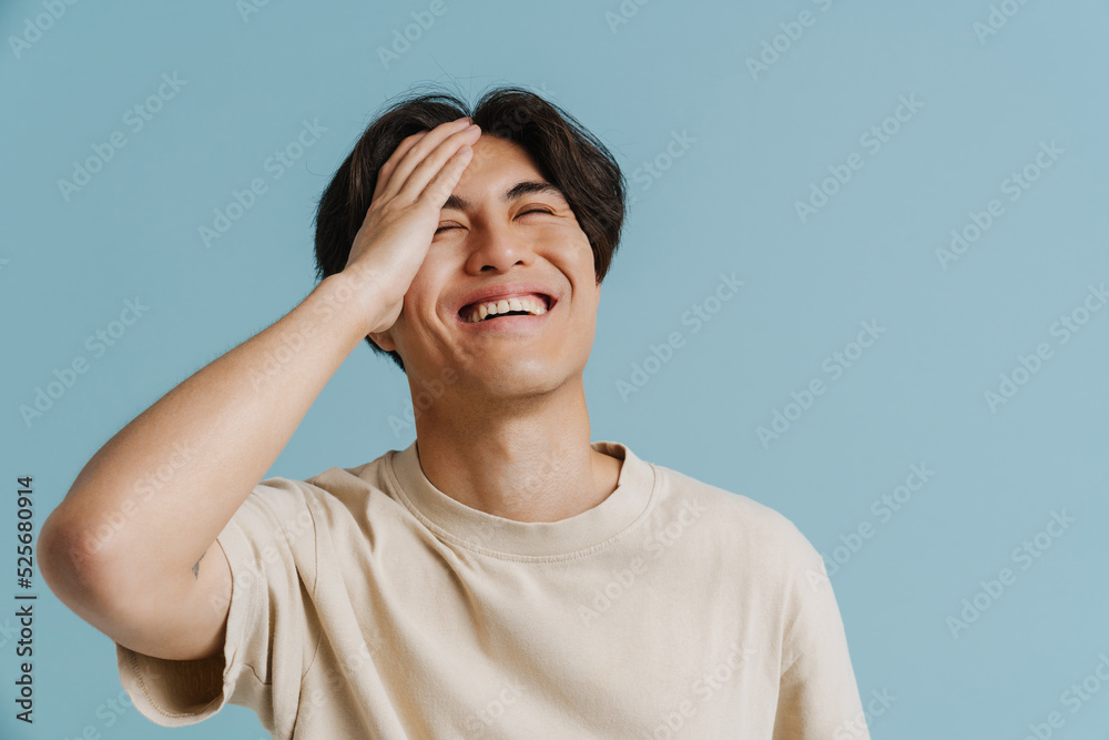 Young handsome laughing asian boy with closed eyes touching forehead Young handsome laughing asian boy with closed eyes touching forehead