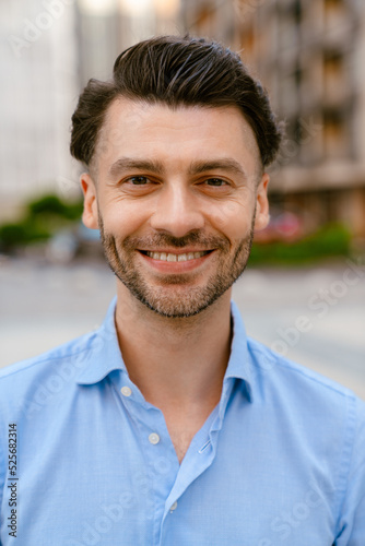 Bristle white man smiling at camera while standing at city street