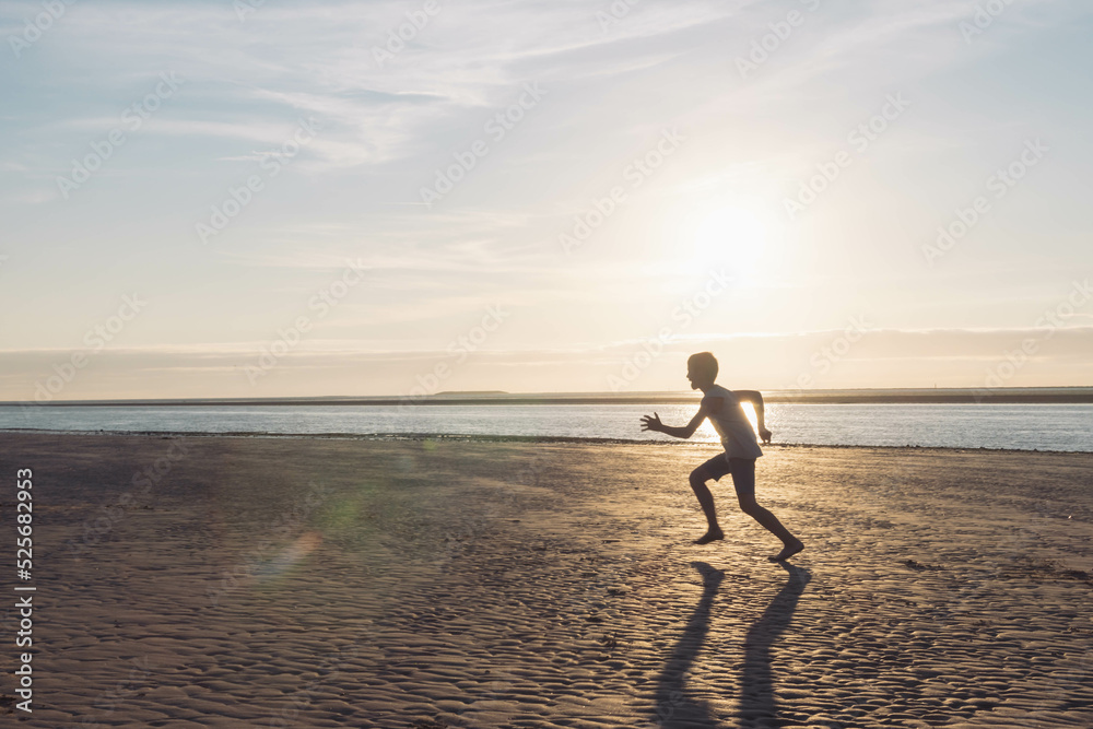 a silhouette of a child running on the beach on the sand near the water, at sunset there is a place for an inscription a silhouette of a child running on the beach on the sand near the water, at sunset there is a place for an inscription