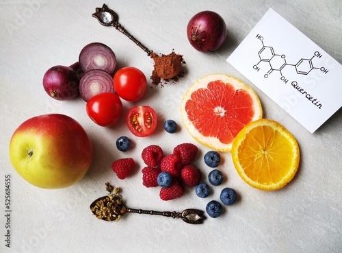 Structural chemical formula of quercetin molecule with fresh fruit and vegetable. Quercetin is a plant pigment (flavonoid). It's found in many plants and foods such as red onions, berries, tomatoes... photo