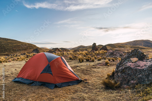 orange colored camp in the mountains in a sunset surrounded by rocks and yellow vegetation in the winter in the andes mountain range