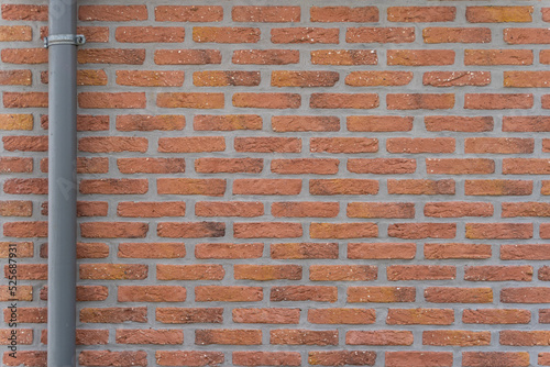 Red brick wall with grey gutter and metal tie