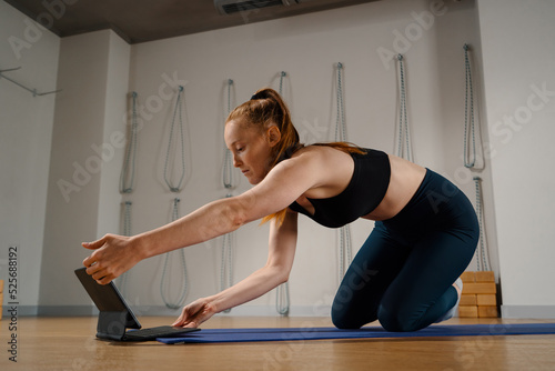 Athletic woman doing yoga pilates stretching online workout in studio or at home.