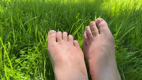 Close up of bare feet lying on a fresh green grass. Summer sunny day.