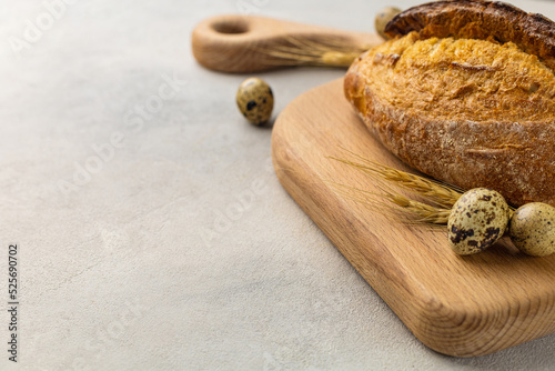 Freshly baked wheat loaf bread on a wooden board on a light background