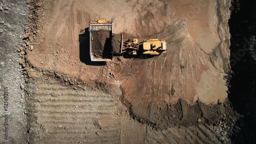 Dump truck and bullzdozer at work. Loading precious minerals in an open pit. Aerial industrial quarry scene. Pollution, environment and ecology concept photo