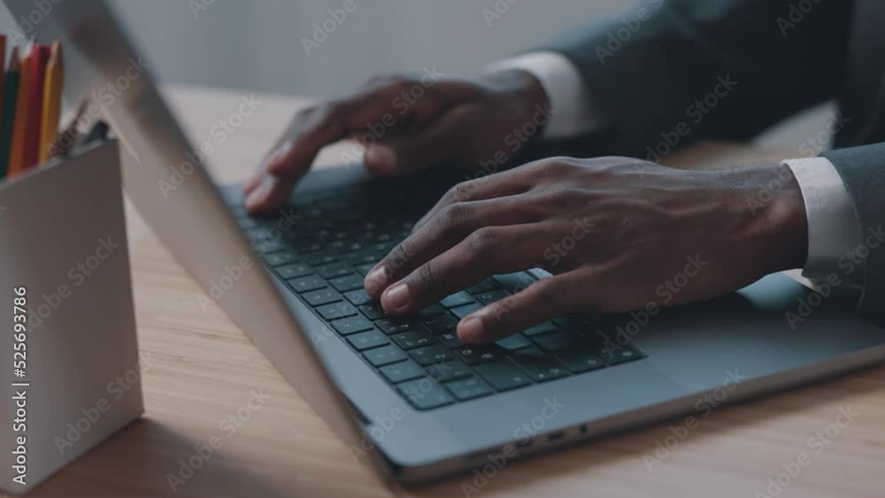 African American man typing text on keyboard with hands close up in office African American man typing text on keyboard with hands close up in office