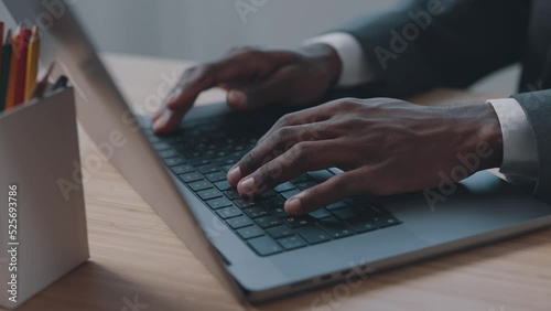 African American man typing text on keyboard with hands close up in office