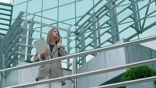 Wallpaper Mural a business woman came out of the office and while talking on the phone approached a railing. elegant woman, holding a computer. Very large and modern style office. Torontodigital.ca